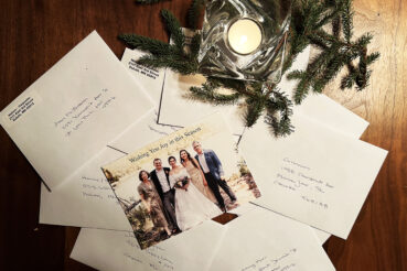 Picture of a stack of addressed cards with a candle and winter greens