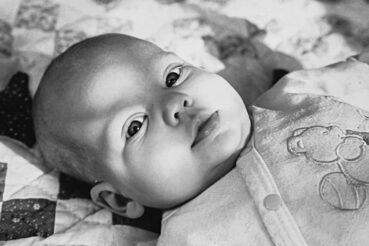 Black and white picture of a baby laying on a blanket